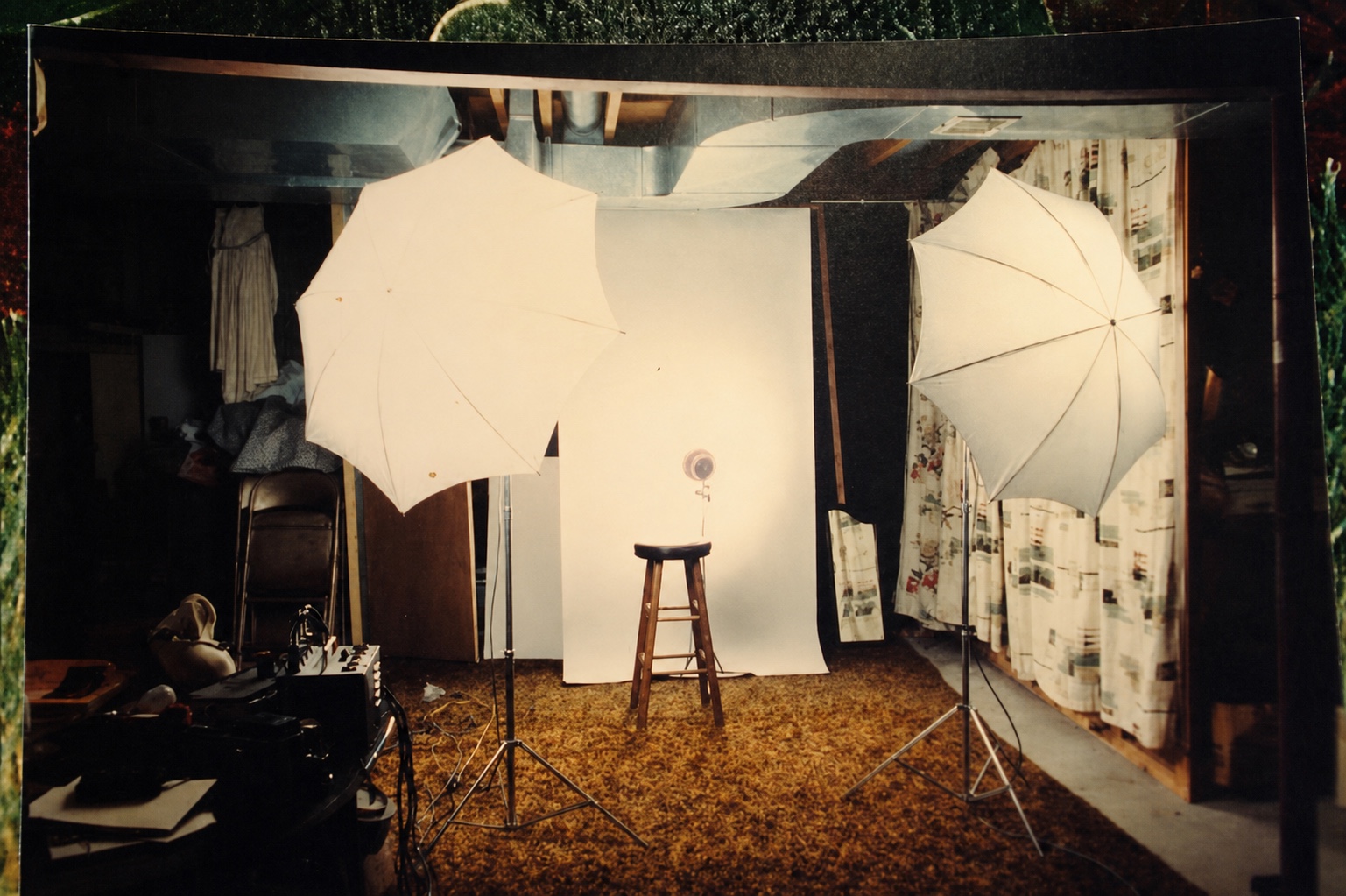 David DeJonge's first basement portrait studio with orange shag carpet, two white lighting umbrellas and patterned curtains