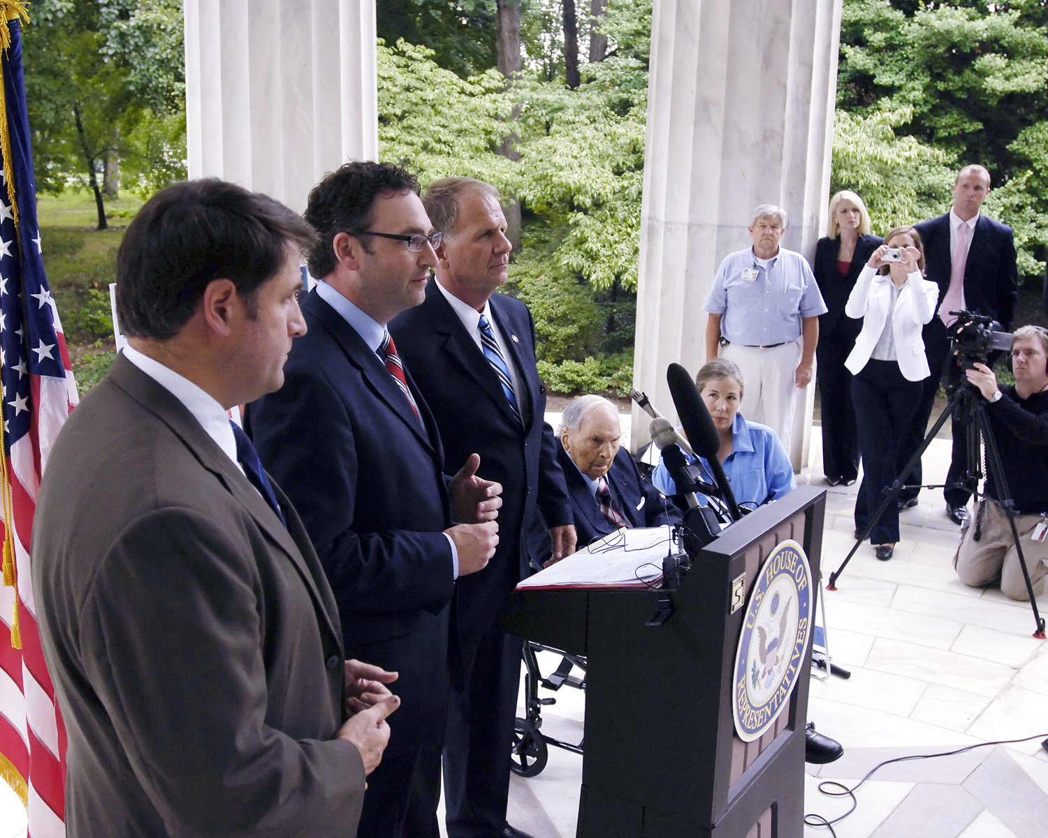 David J. DeJonge speaks beside Edwin Fountain and Representative Ted Poe at the District of Columbia War Memorial while Frank Buckles sits behind the podium