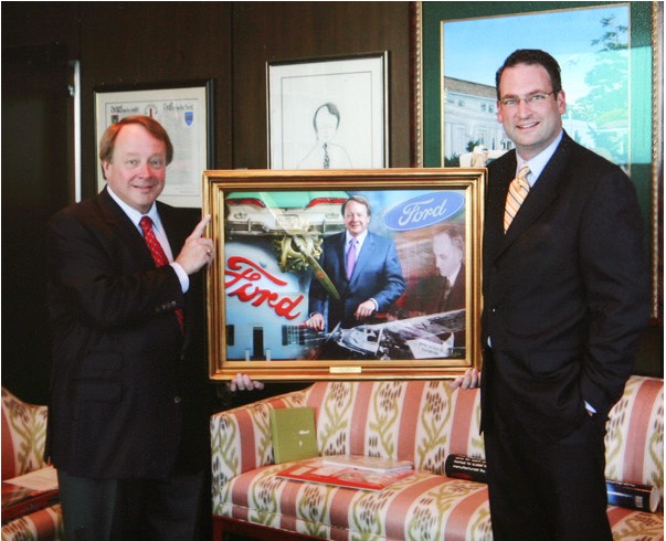 Edsel B. Ford II and David DeJonge holding DeJonge’s commissioned Ford portrait at Ford headquarters