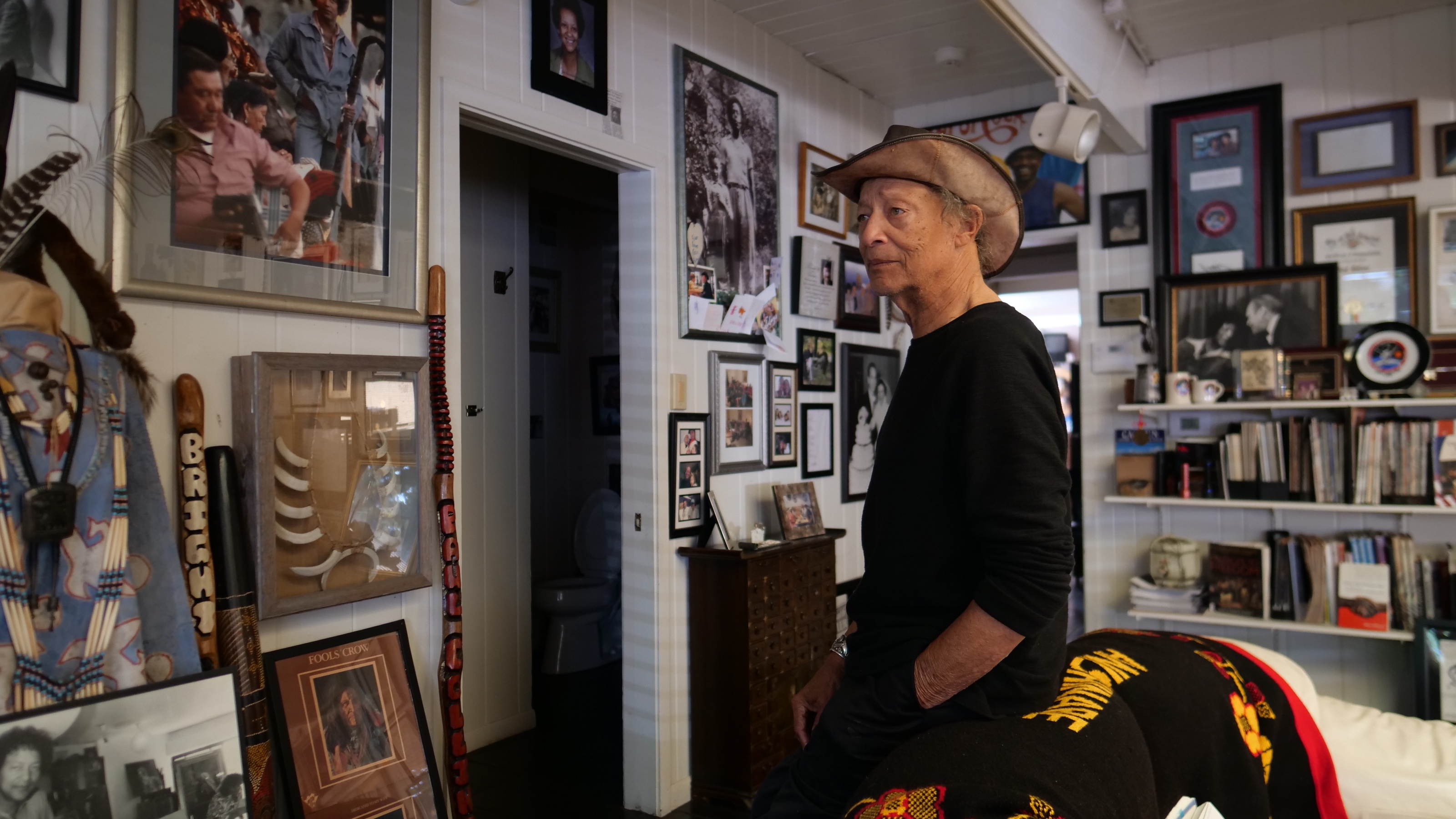 Paul Collins seated in his Grand Rapids studio, surrounded by books, artwork, and personal history