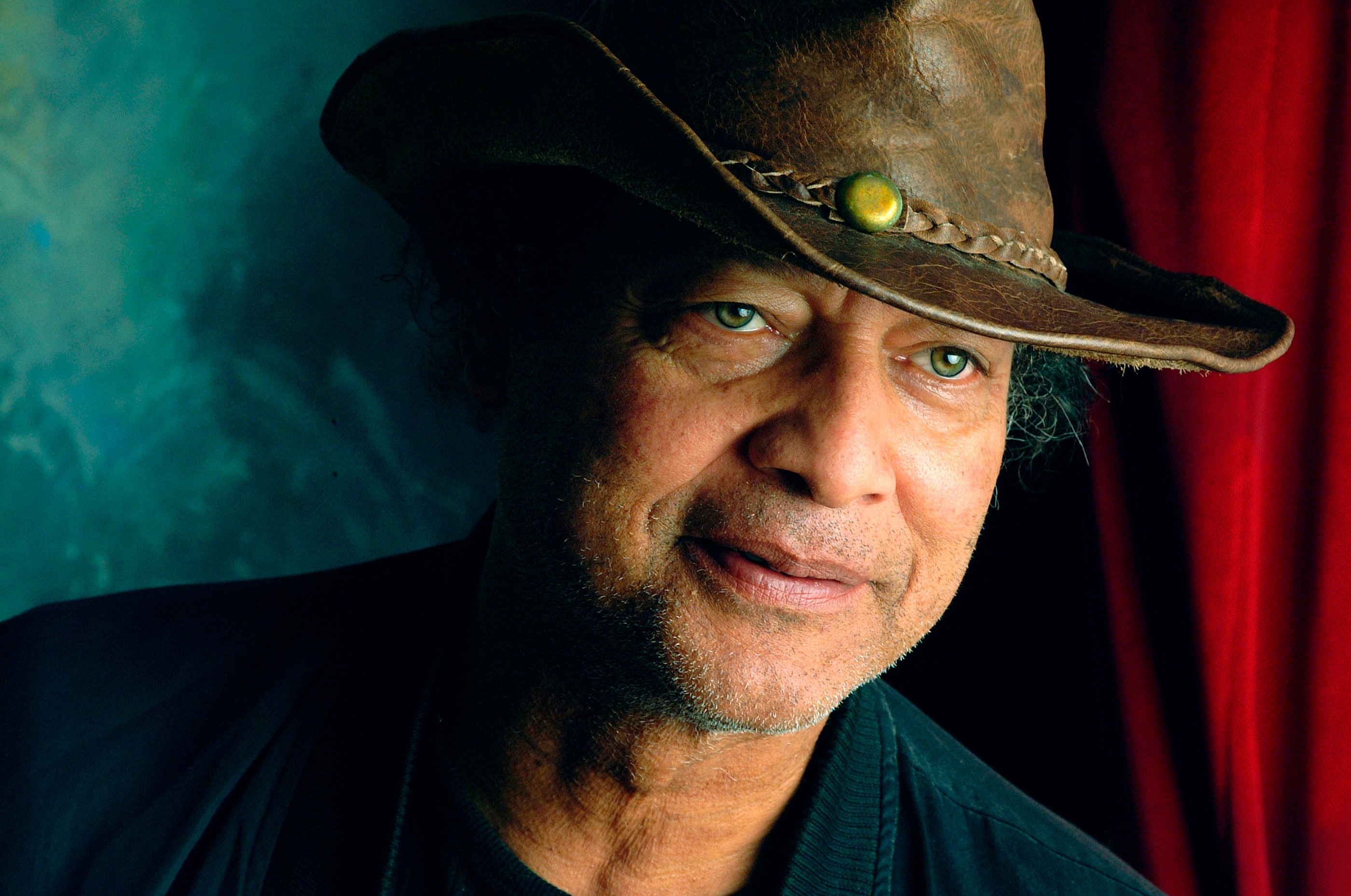 Close portrait of artist and activist Paul Collins wearing a broad-brimmed hat, with a composed expression