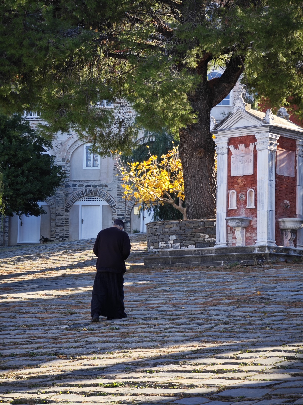 A monk crossing a stone courtyard on Mount Athos